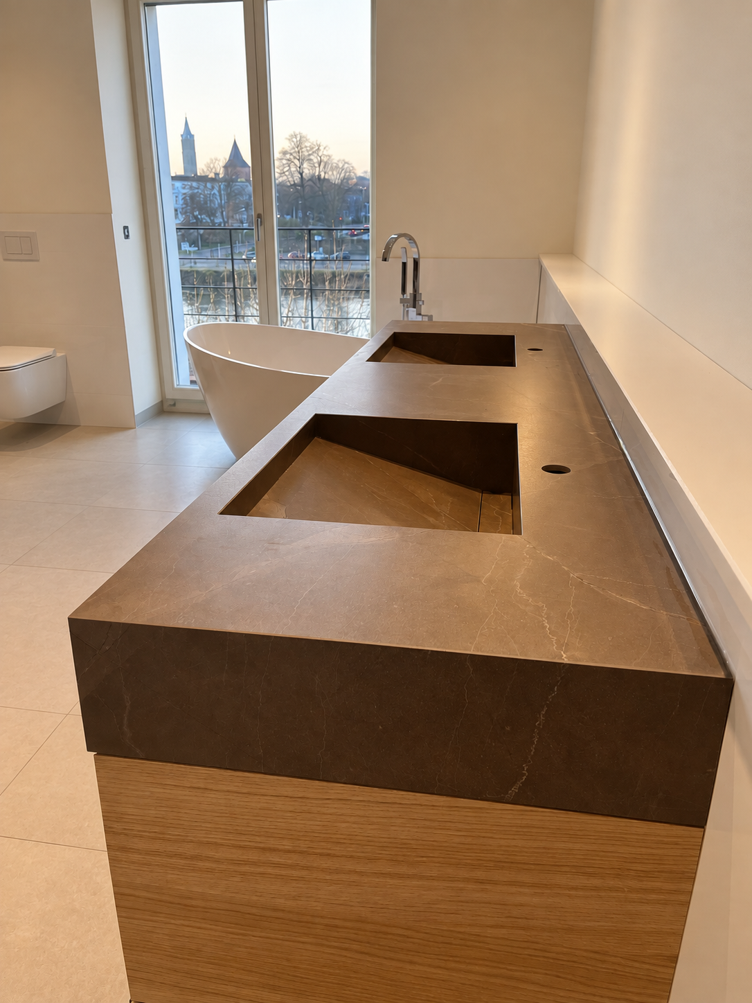 Brauner Steinwaschtisch mit zwei integrierten Becken und Holzfront vor einer freistehenden Badewanne